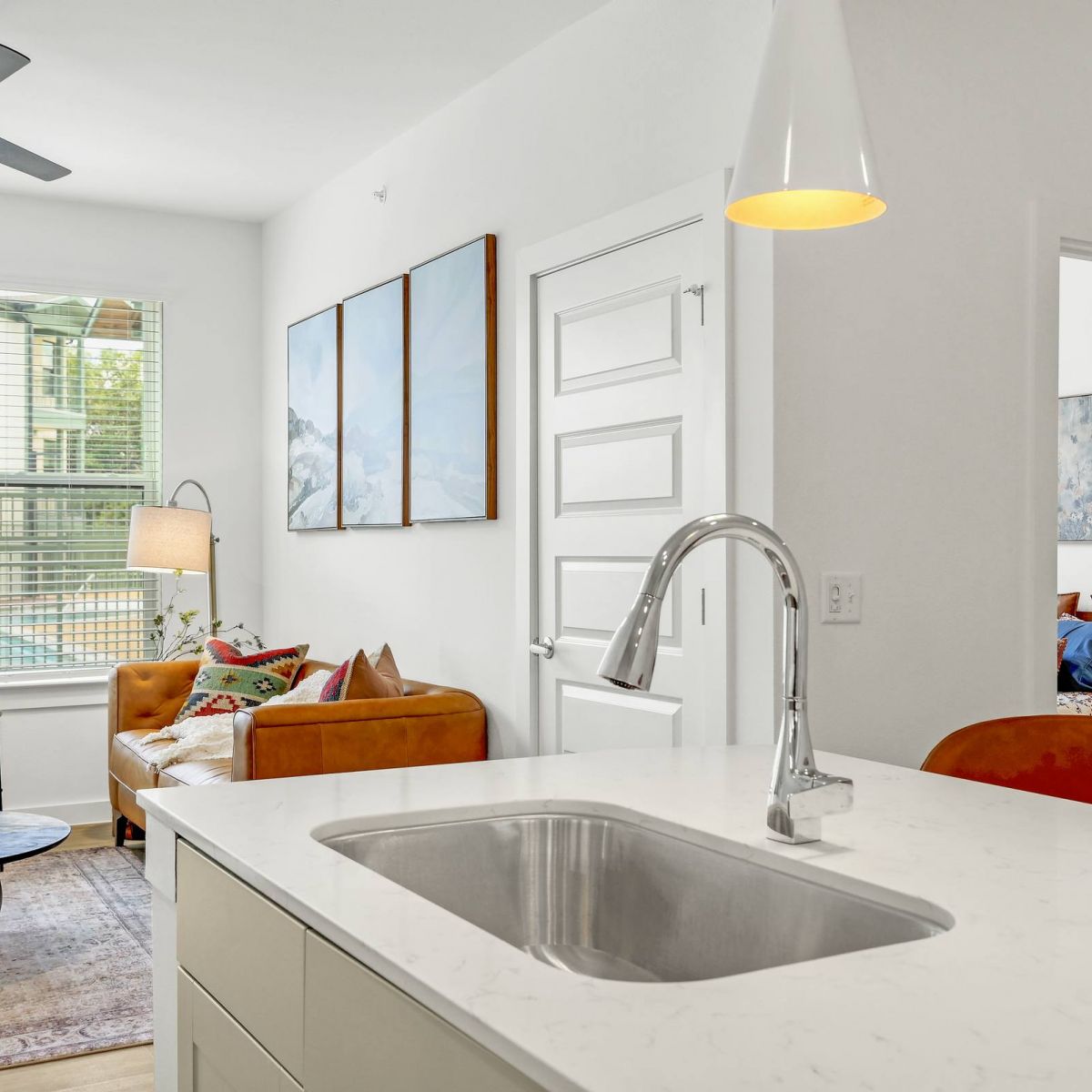Modern apartment with a kitchen island, cozy living area, and bedroom visible through an open door at Bluff View at Frederick Creek.