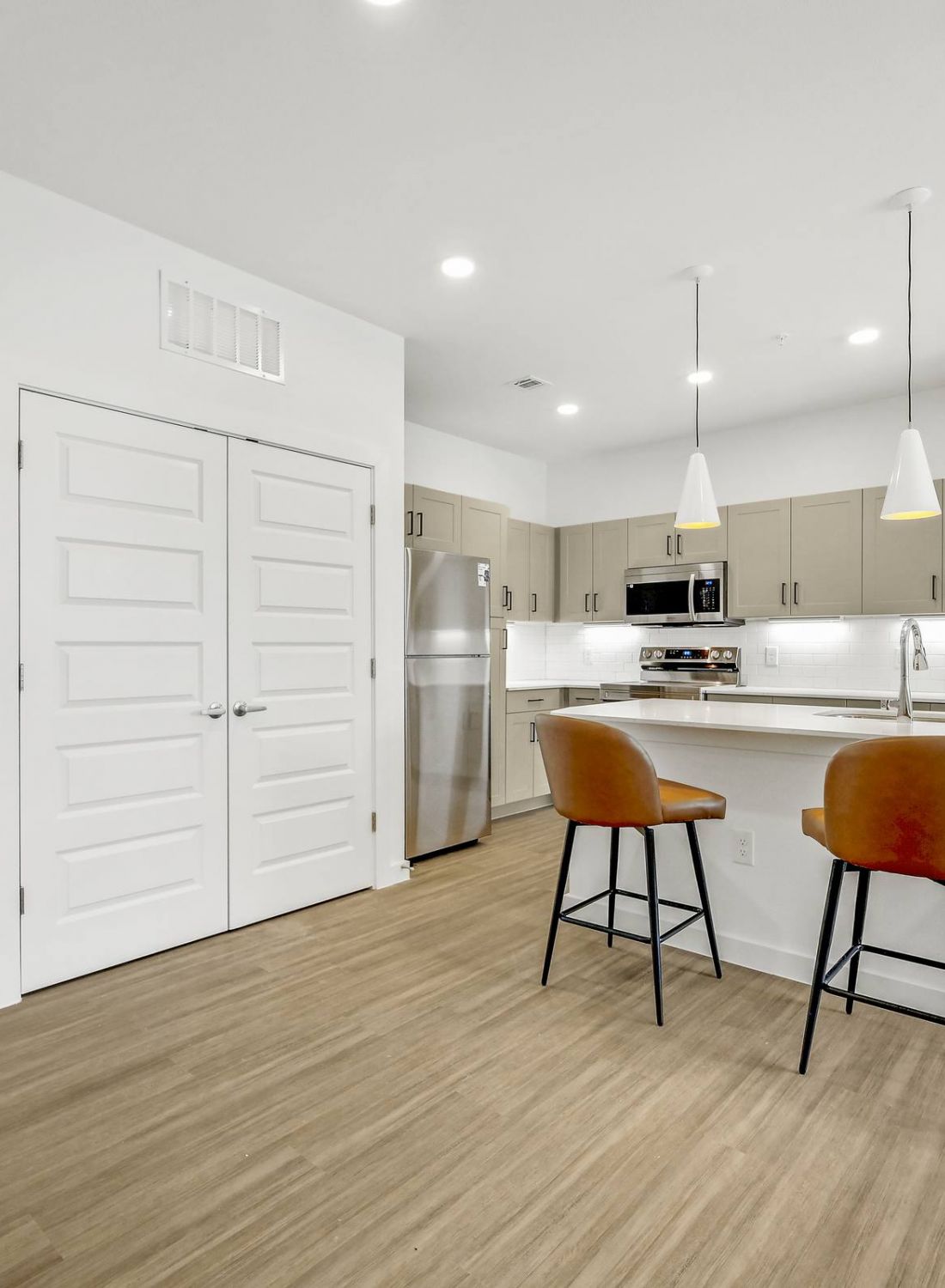 Modern kitchen with bar seating, stainless steel appliances, and wood flooring in a bright, open space at Bluff View at Frederick Creek.