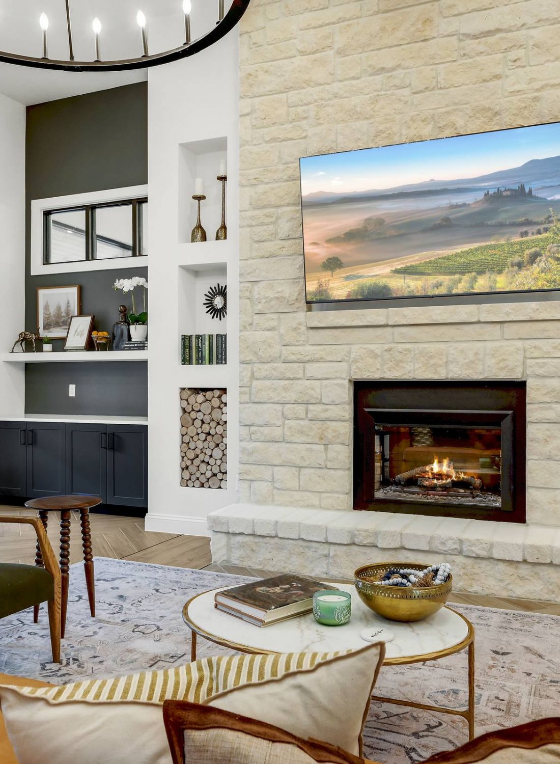 Modern living room with a stone fireplace, built-in shelves, and a TV mounted above the mantel. at Bluff View at Frederick Creek.